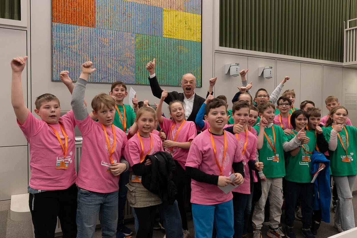 Een groepje kinderen staat samen met de Voorzitter op de foto. Ze juichen.