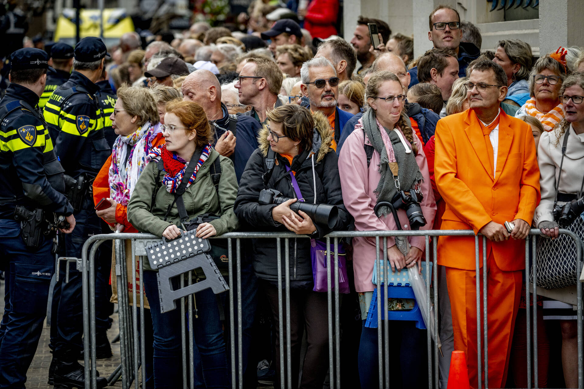 Mensen staan achter hekken te kijken naar de Koninklijke Stoet.