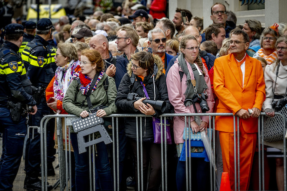 Mensen staan achter hekken te kijken naar de Koninklijke Stoet.