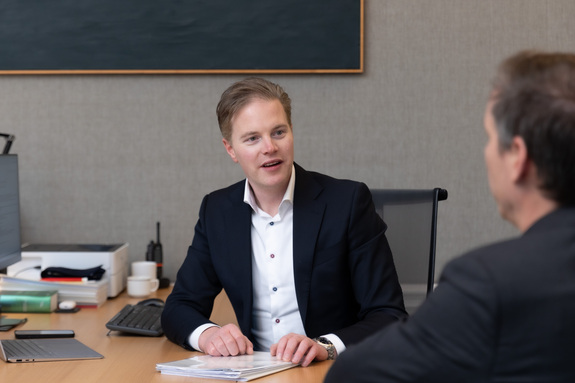 Collega's praten met elkaar aan een bureau.