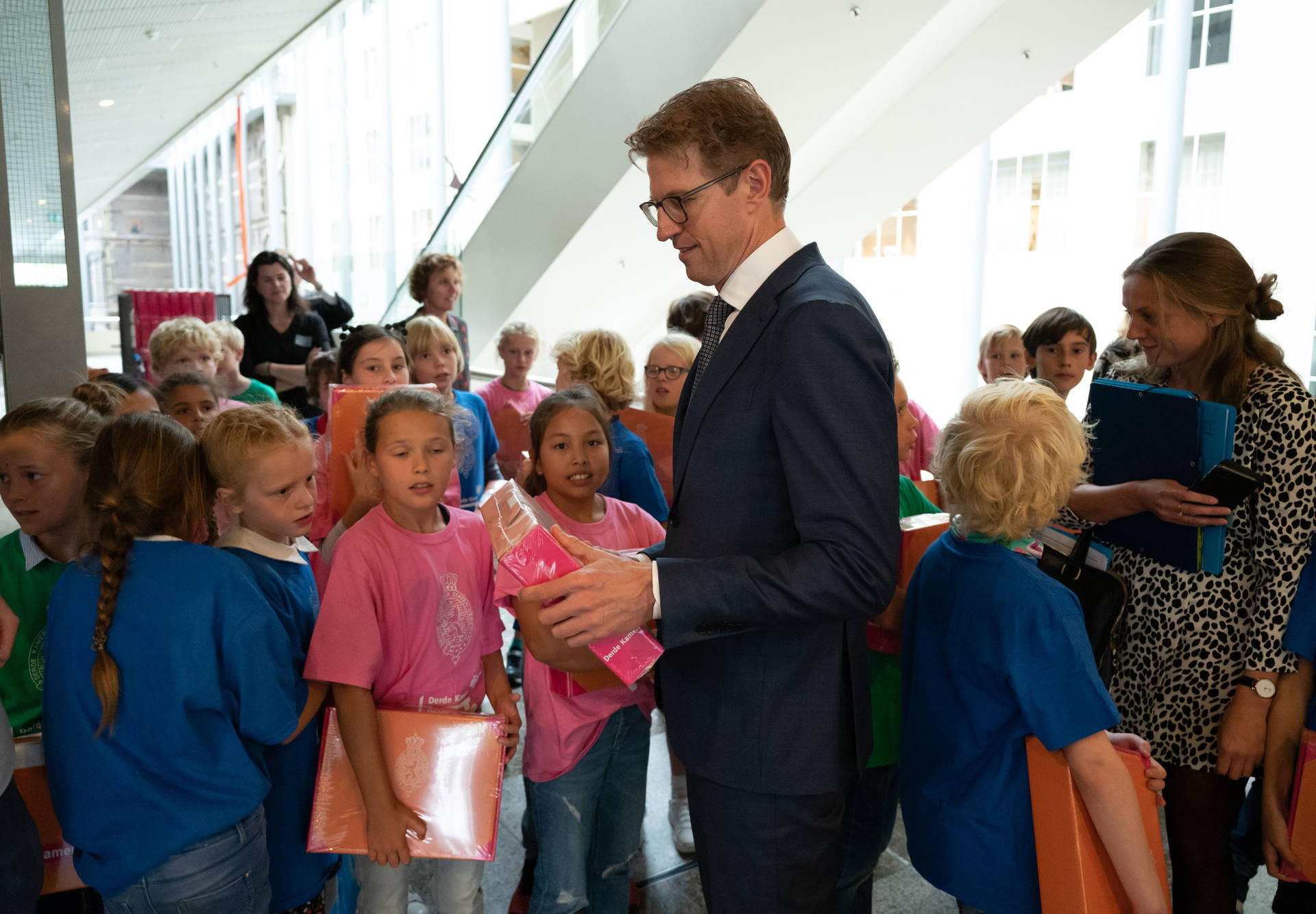 Minister Dekker neemt een koffertje in ontvangst