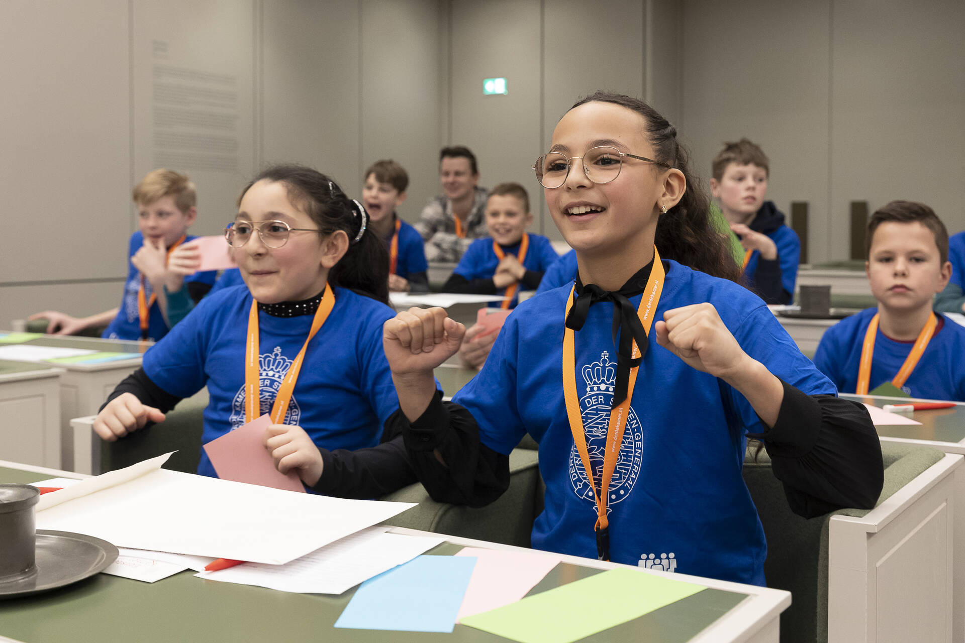 Kinderen zitten in bankjes en juichen.